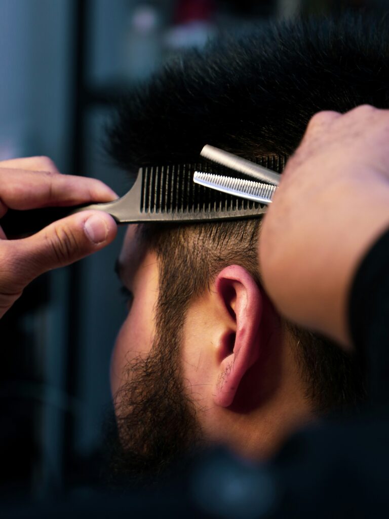 [ALT_TEXT: Primer plano de un barbero cortando un mullet a un cliente, moldeando cuidadosamente los laterales.]