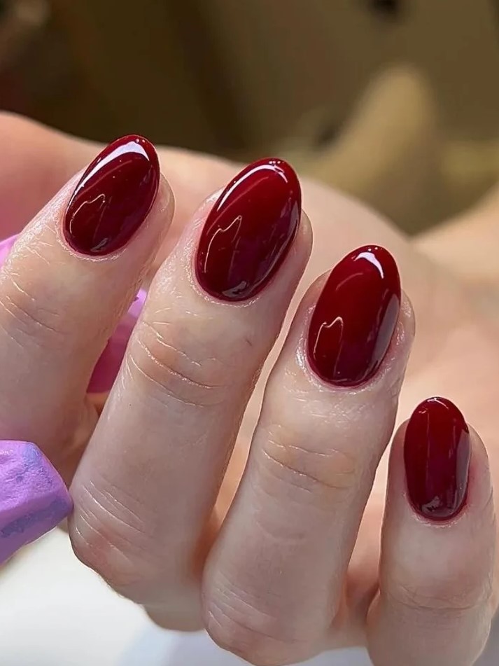 Primer plano de manicura BIAB en tono rojo oscuro