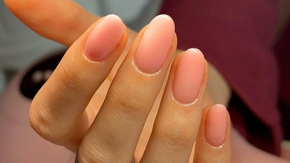 Primer plano de manicura BIAB en tono rosa translcido