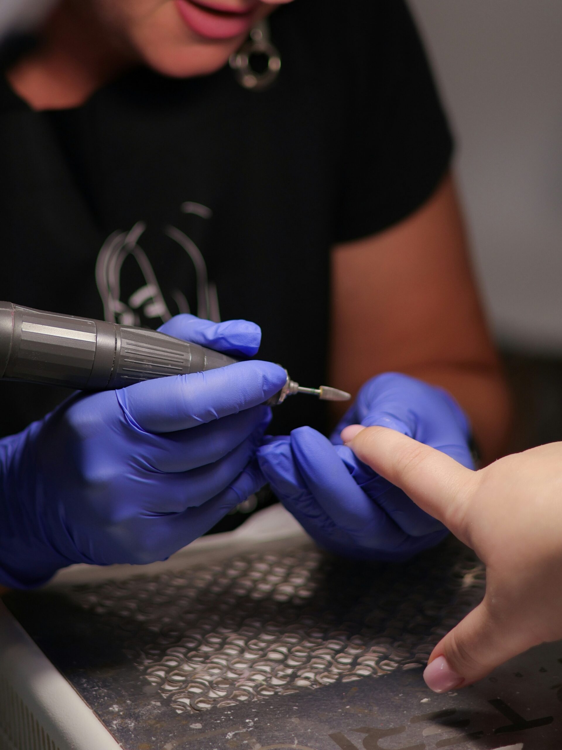 Técnico de uñas utilizando torno de lima en salón para retirar la manicura BIAB