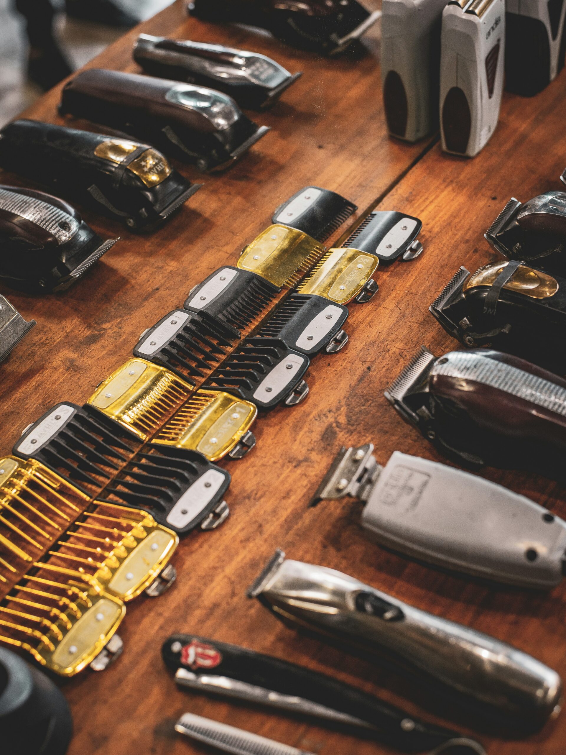 Vista cenital de herramientas de barbería sobre una repisa de madera, incluyendo maquinillas y peines guía