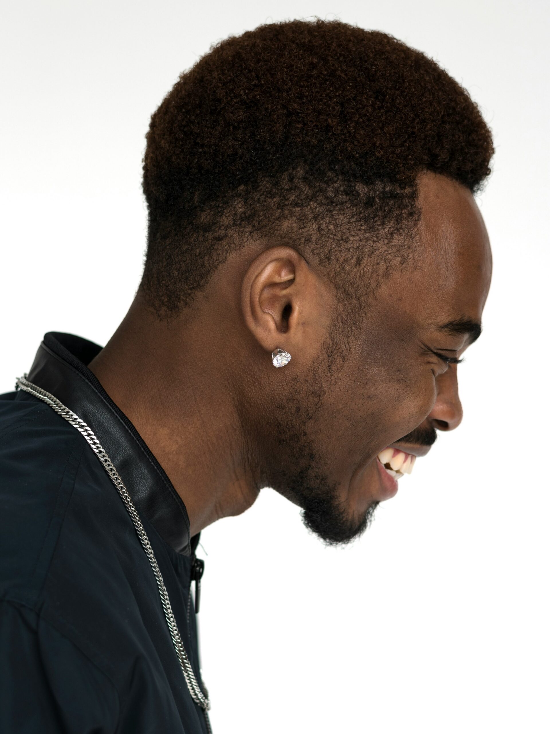 Perfil lateral de un hombre sonriente con cabello afro y un high taper fade
