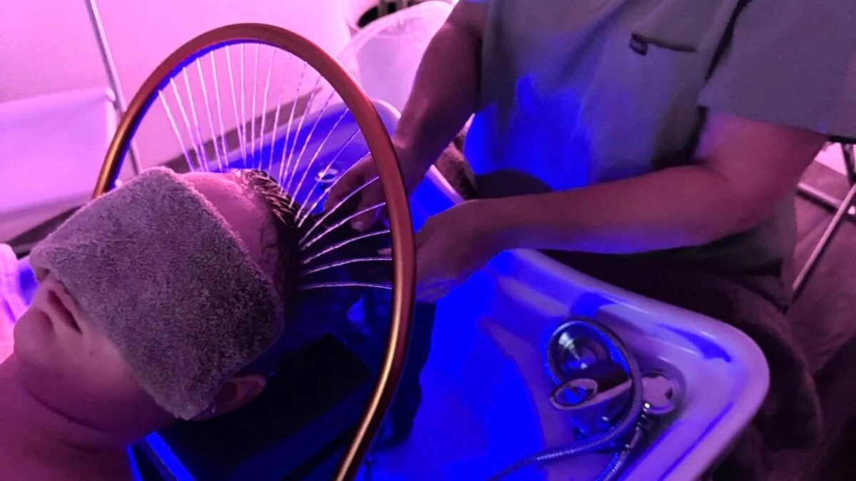 Vista cenital de un terapeuta lavando el pelo de una clienta durante un head spa japonés