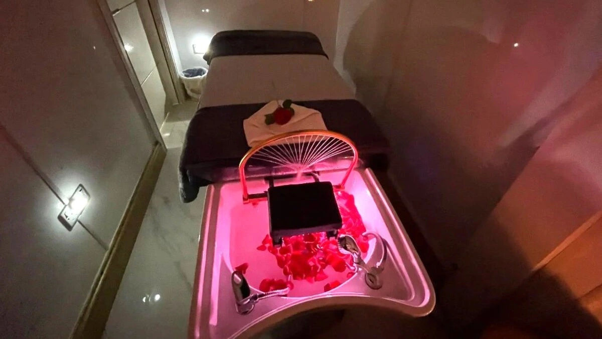 Interior de una sala de head spa japonés acogedora con luz tenue, con una camilla, un lavacabezas con pétalos y equipo de spa