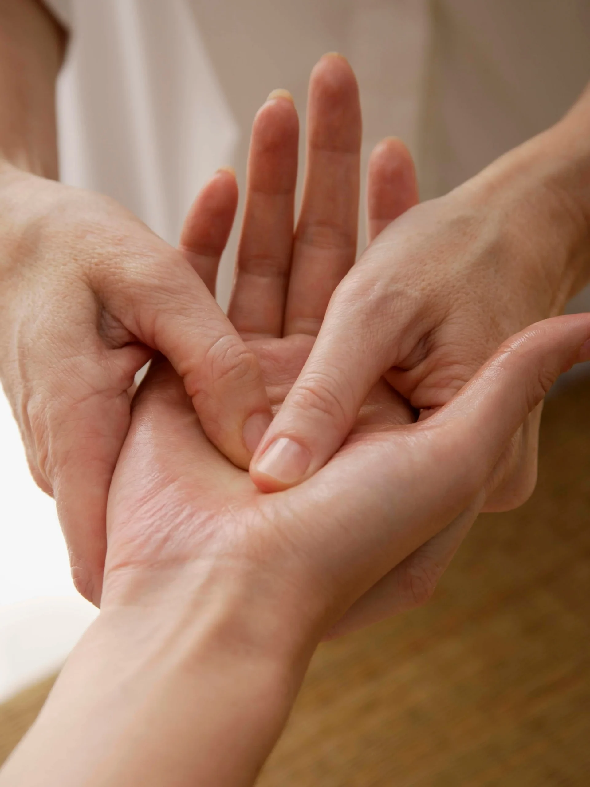 Primer plano de un reflexólogo trabajando la mano de una clienta