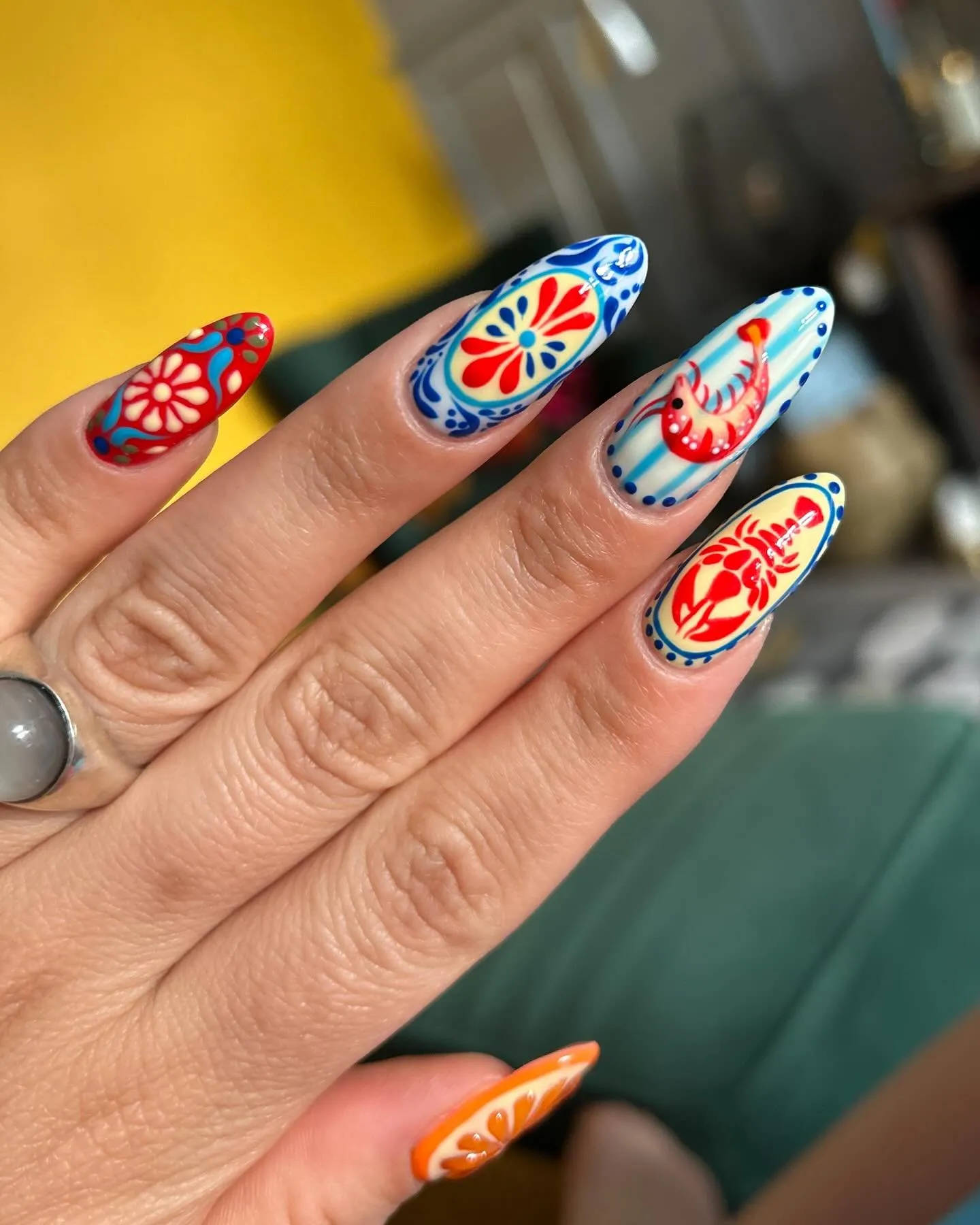 Nail art Destination manis en uñas de forma almendrada, con motivos de inspiración mediterránea en rojo, azul y naranja