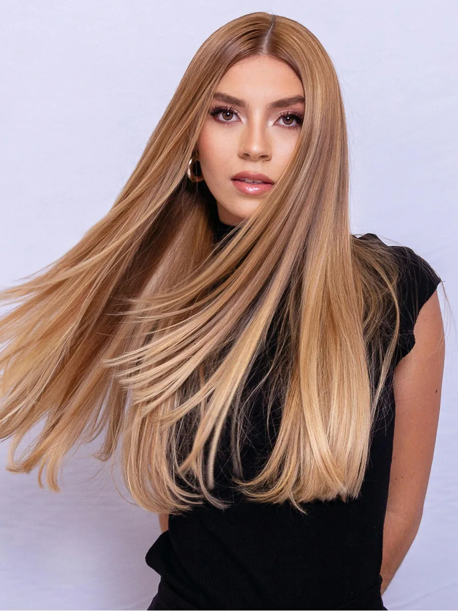 Retrato de estudio de una mujer agitando su larga melena rubia caramelo y brillante