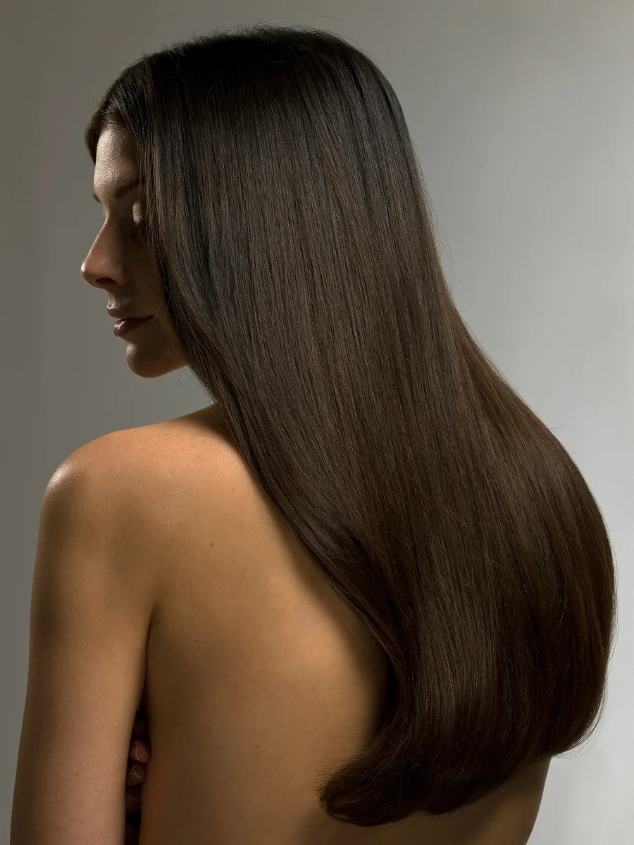 Retrato de estudio de perfil de una mujer con una larga melena castaña y brillante