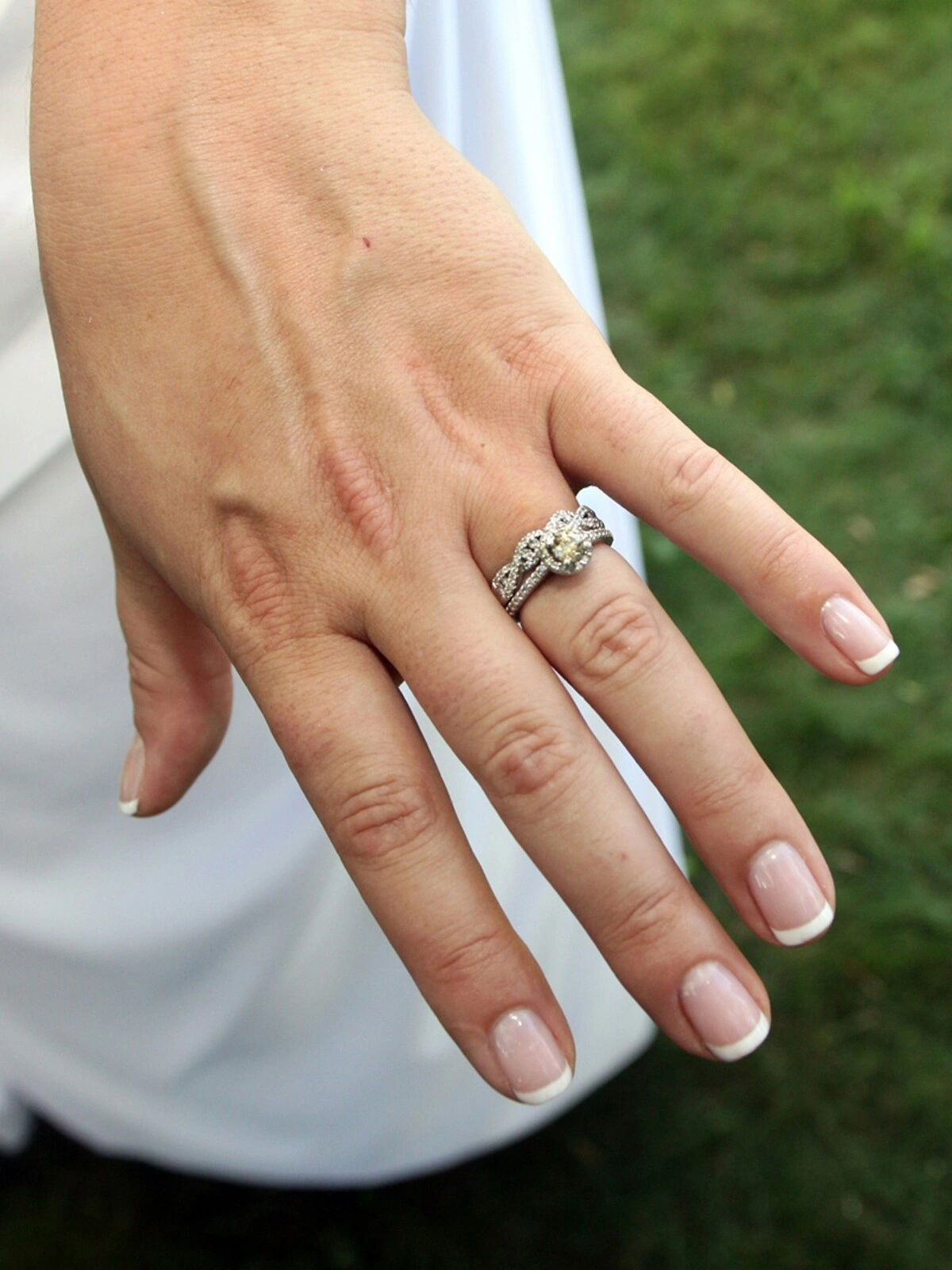 La mano de una mujer con una cuidada manicura francesa en una combinación clásica de nude y blanco sobre uñas cortas de forma cuadrada-ovalada