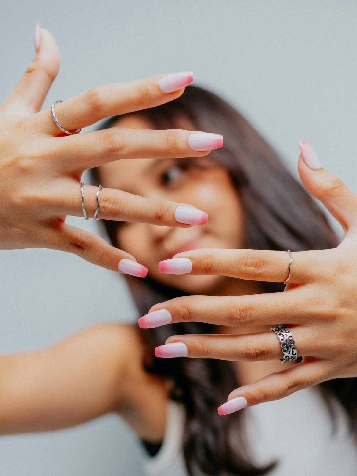 Una mujer muestra las manos a la cámara con una manicura francesa en versión ombré, de base rosa claro y puntas rosa intenso sobre uñas bailarina