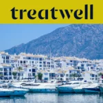 El puerto deportivo de Puerto Banús, en Marbella, rodeado de edificios blancos y yates amarrados con las montañas al fondo, bajo una banderola amarilla de Treatwell.