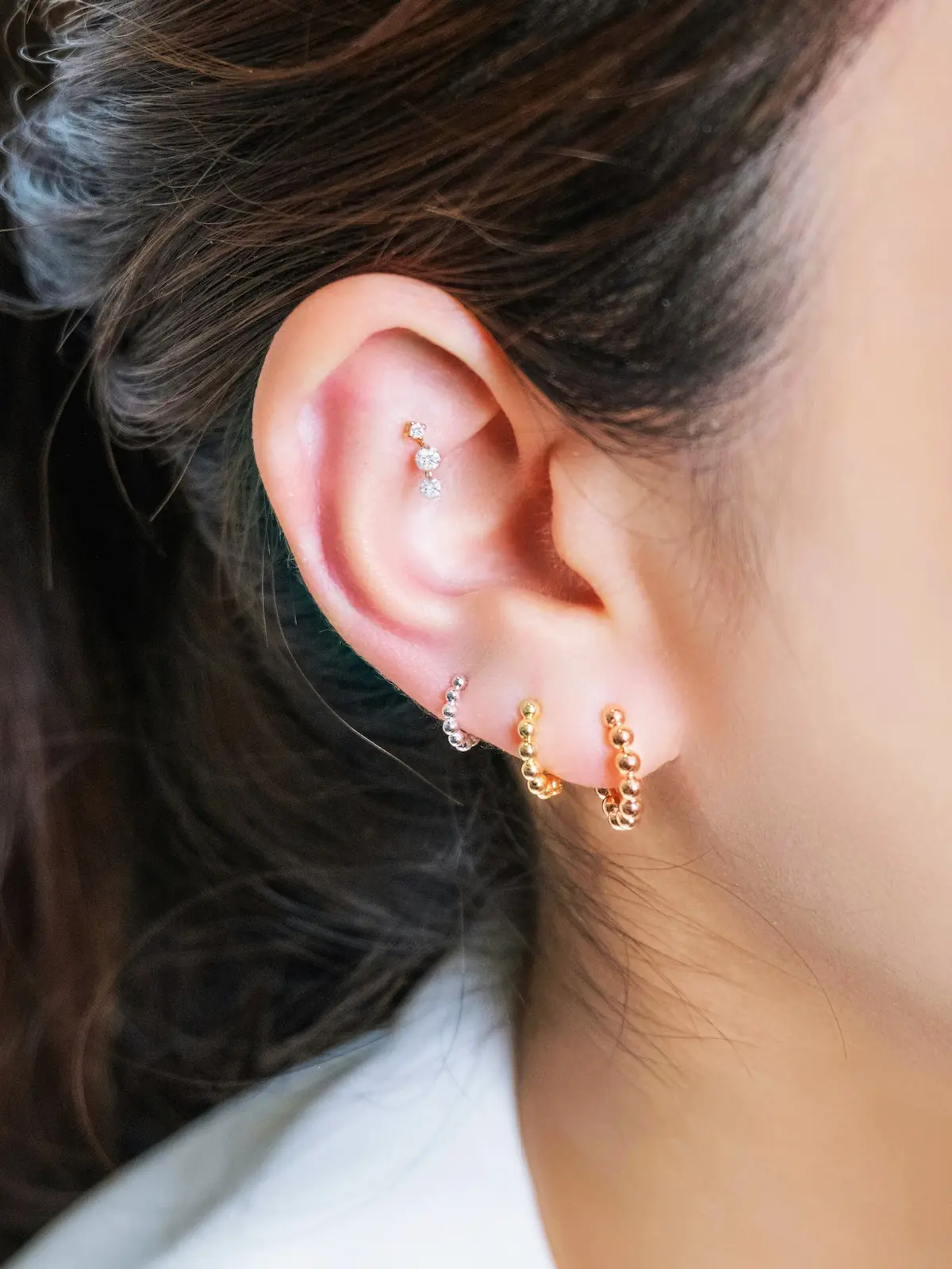 Primer plano de la oreja de una mujer con varios aros y un pendiente en el hélix