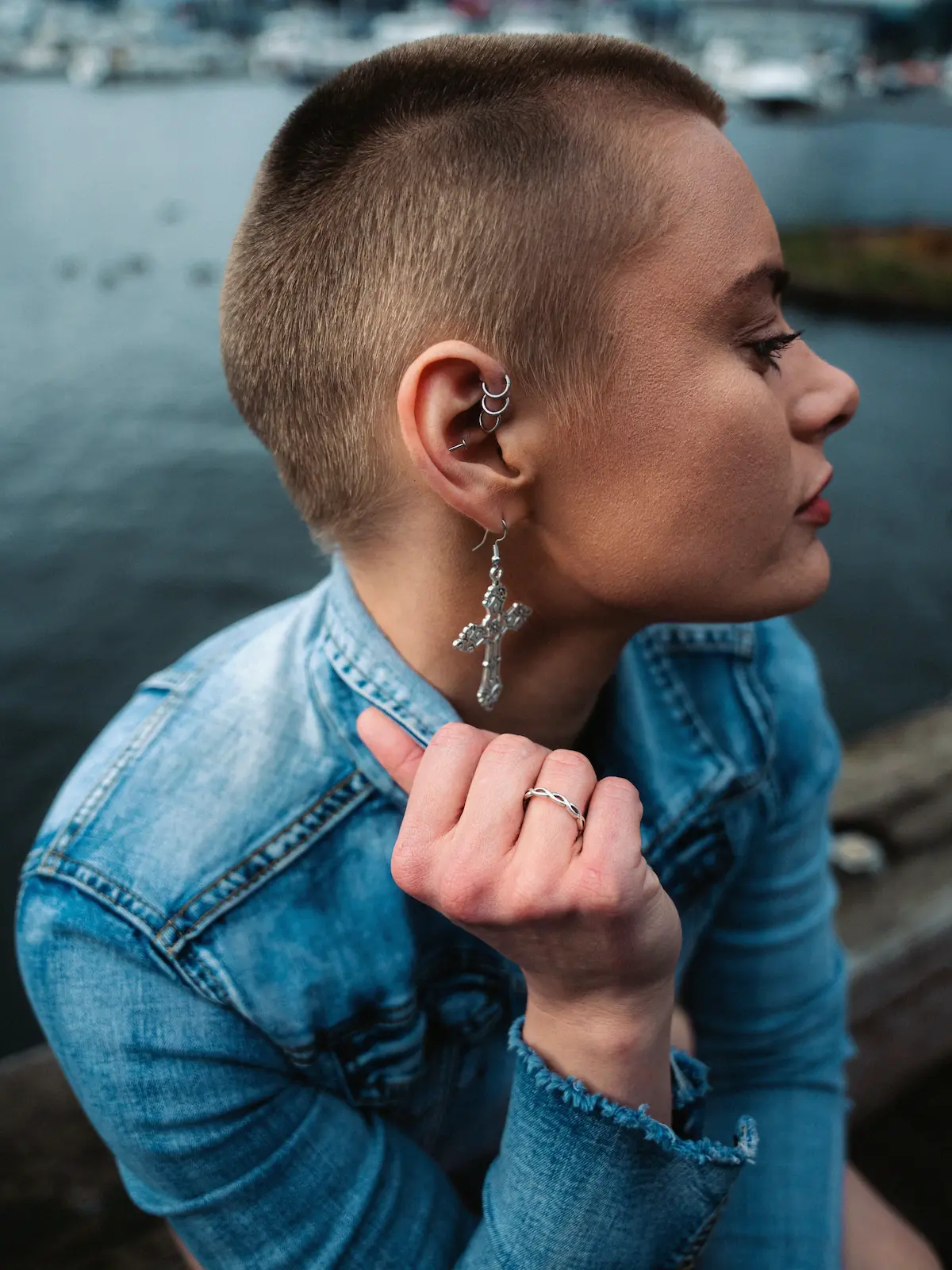 Foto cenital de una mujer con piercings de forward helix, hélix y lóbulo, sentada junto a un río en la ciudad