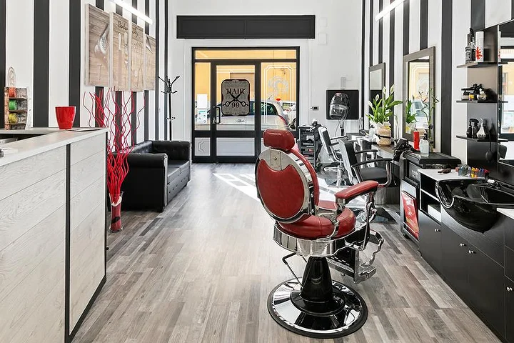 Sillón de barbero vintage rojo en Hair 99 en Alghero, con sus características paredes a rayas blancas y negras.