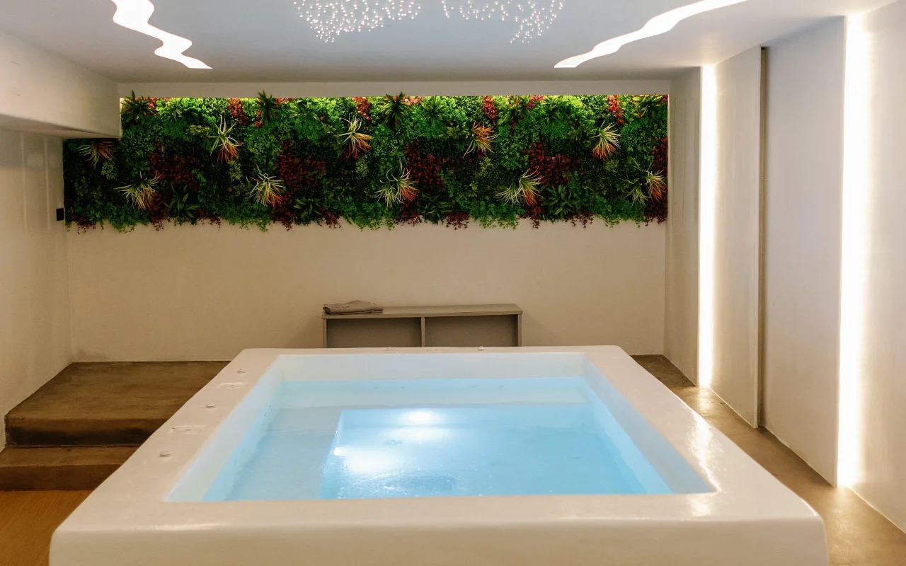 La piscina de hidroterapia de Liana Spa Therapy en Naxos, suavemente iluminada desde dentro, bajo una pared vegetal de colores con plantas preservadas y un techo salpicado de diminutas luces-estrella.