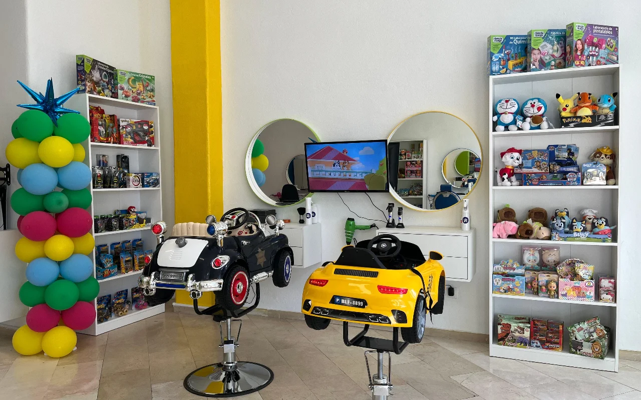 La zona infantil de Peluplay en Benalmádena, donde las sillas de peinado tienen forma de coche de juguete, con estanterías llenas de dibujos, espejos redondos y una columna de globos.