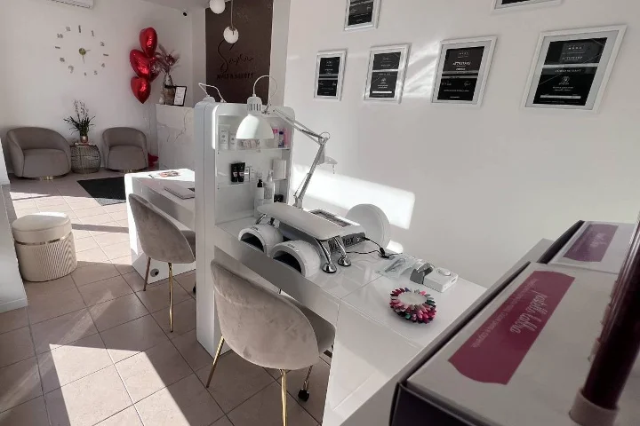 Salón de uñas blanco Sara Nails&Beauty en Tortolì con sillones de terciopelo gris y certificados enmarcados en la pared.