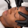Primer plano de una esteticista realizando dermaplaning a una clienta en un centro de belleza