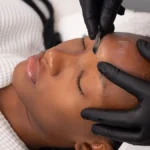 Primer plano de una esteticista realizando dermaplaning a una clienta en un centro de belleza