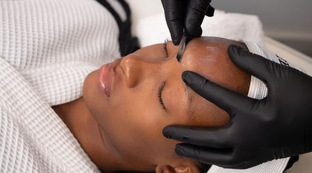 Primer plano de una esteticista realizando dermaplaning a una clienta en un centro de belleza