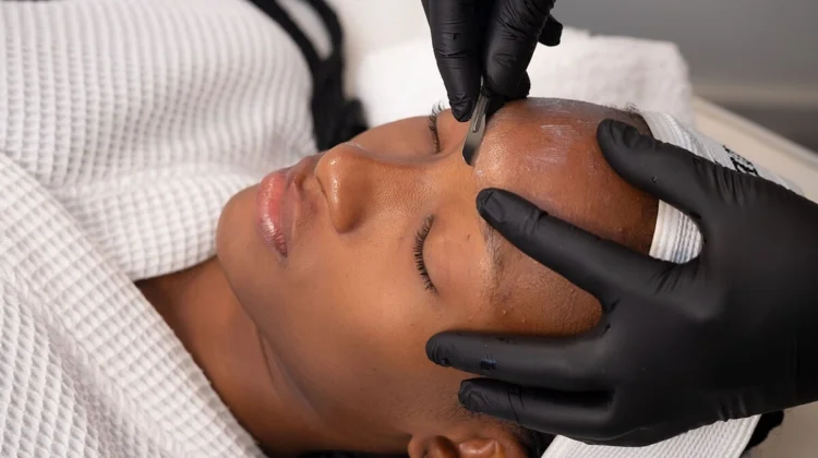 Primer plano de una esteticista realizando dermaplaning a una clienta en un centro de belleza