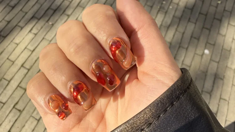 Uñas lava nails con remolinos ámbar y rojos sobre base transparente