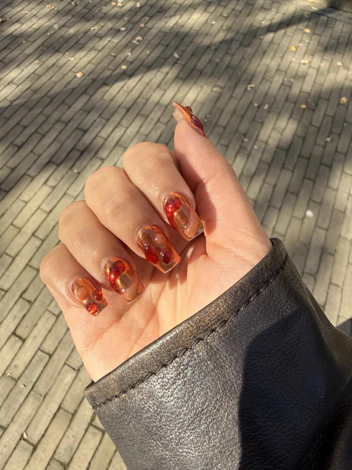 Uñas lava nails con remolinos ámbar y rojos sobre base transparente