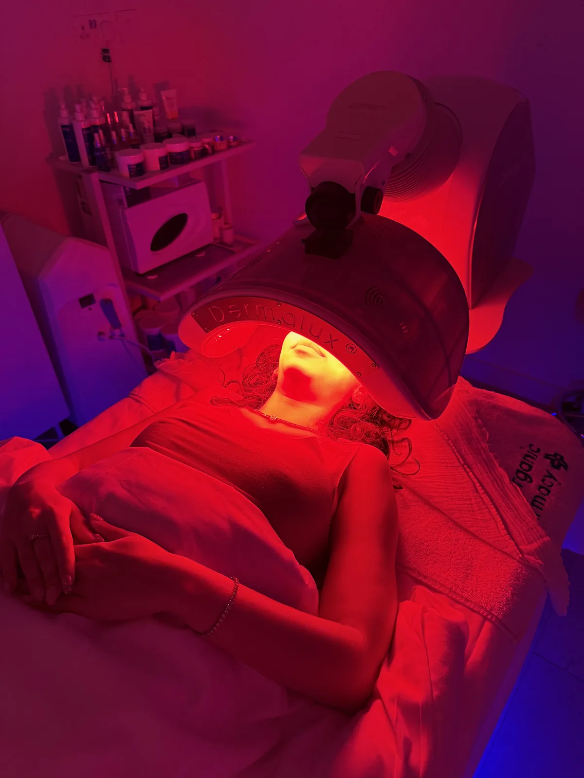 Mujer relajada bajo un panel LED de luz roja durante un tratamiento de spa
