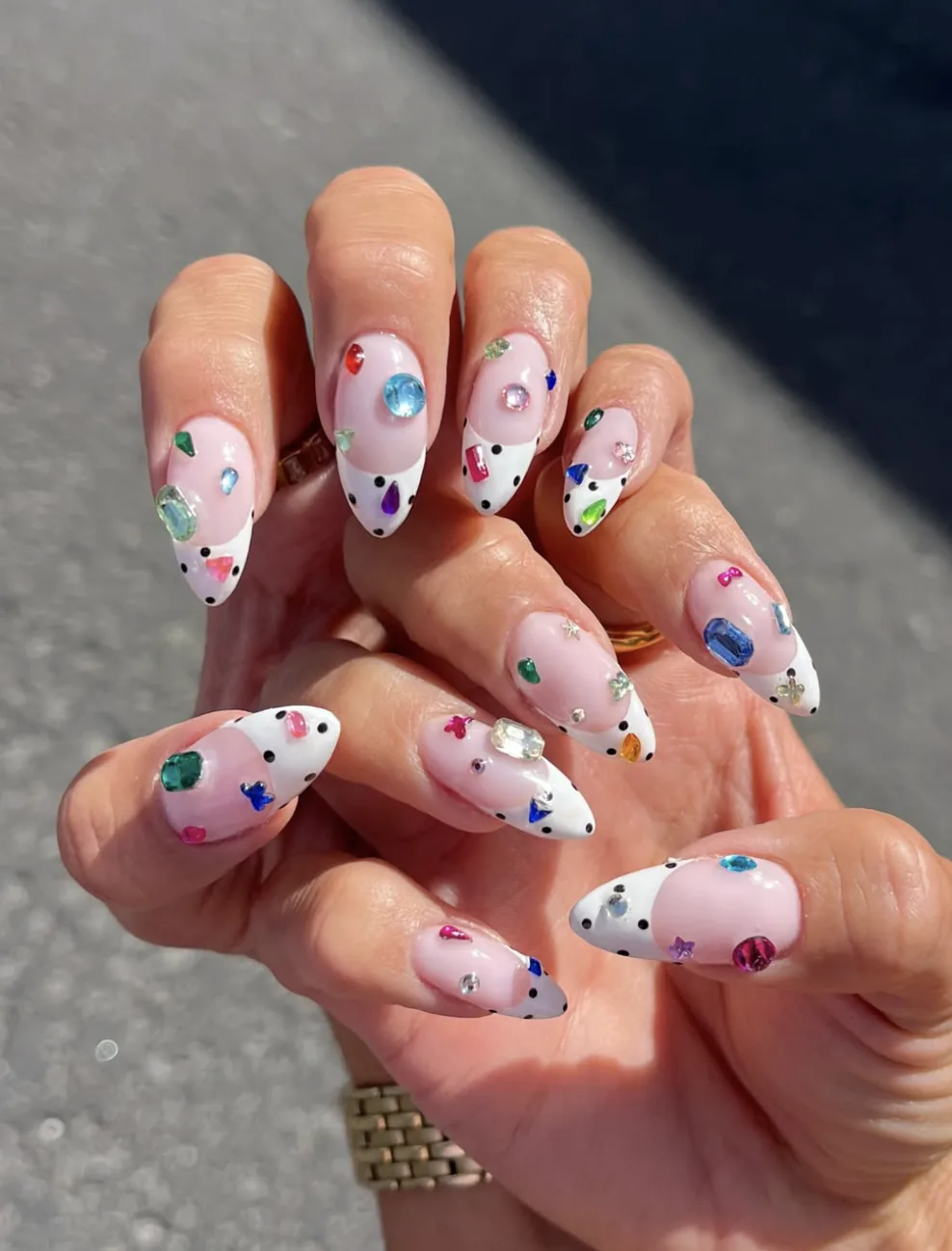 Uñas almendradas estilo bedazzled con strass de colores y puntas blancas de lunares